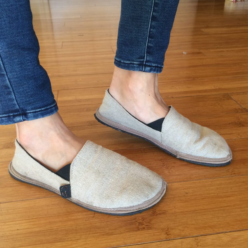 A pair of feet from the side wearing the Unshoes Terra Vida vegan hemp barefoot slip ons in natural color