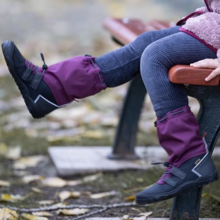 A close up of a child sitting on a bench swinging her legs wearing Koel Rana kids barefoot winter shoes