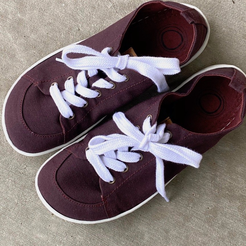 A pair of Mukishoes vegan casual barefoot sneakers in Plum color sitting on concrete