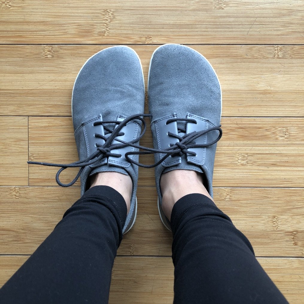 top down view of feet wearing Zaqq Piquant barefoot casual sneakers in grey on wood floor