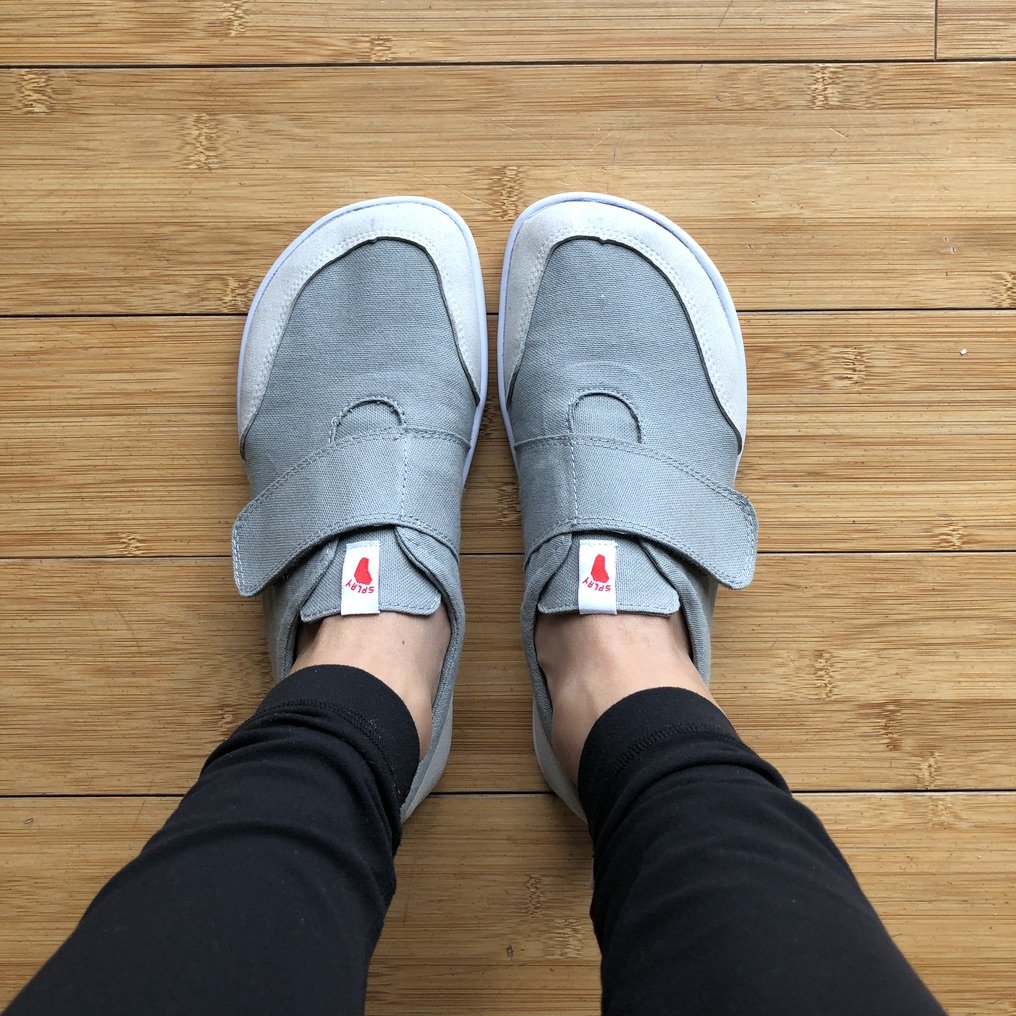 a close up top down view of feet in Splay Athletics hammerhead velcro sneakers on wood floor