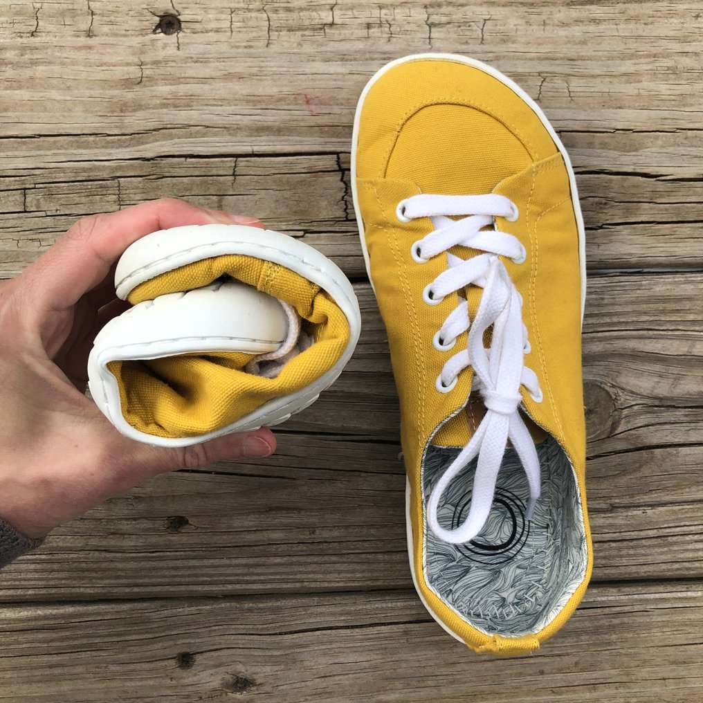 The mukishoes barefoot sneaker review, showing a hand holding a rolled up shoe