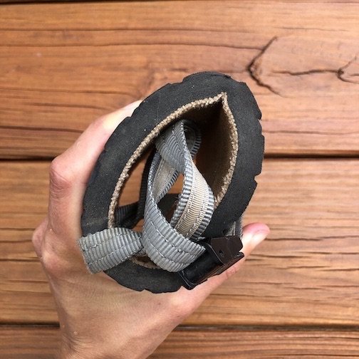 close up of hand holding rolled up Earth Runners Alpha sandals with charcoal strap