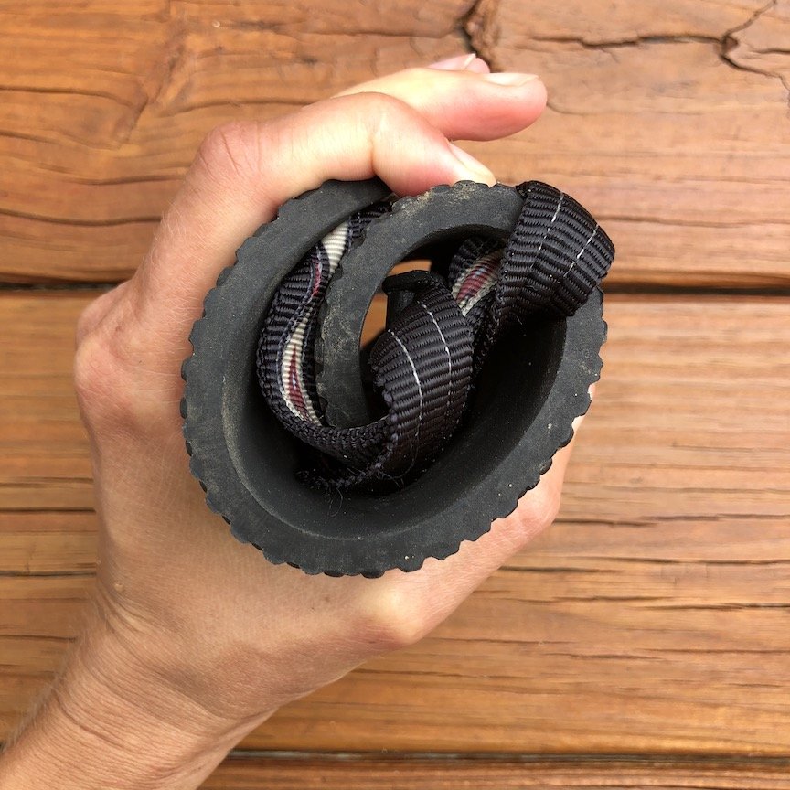 close up of hand holding rolled up Earth Runners Elemental sandals with tribal strap