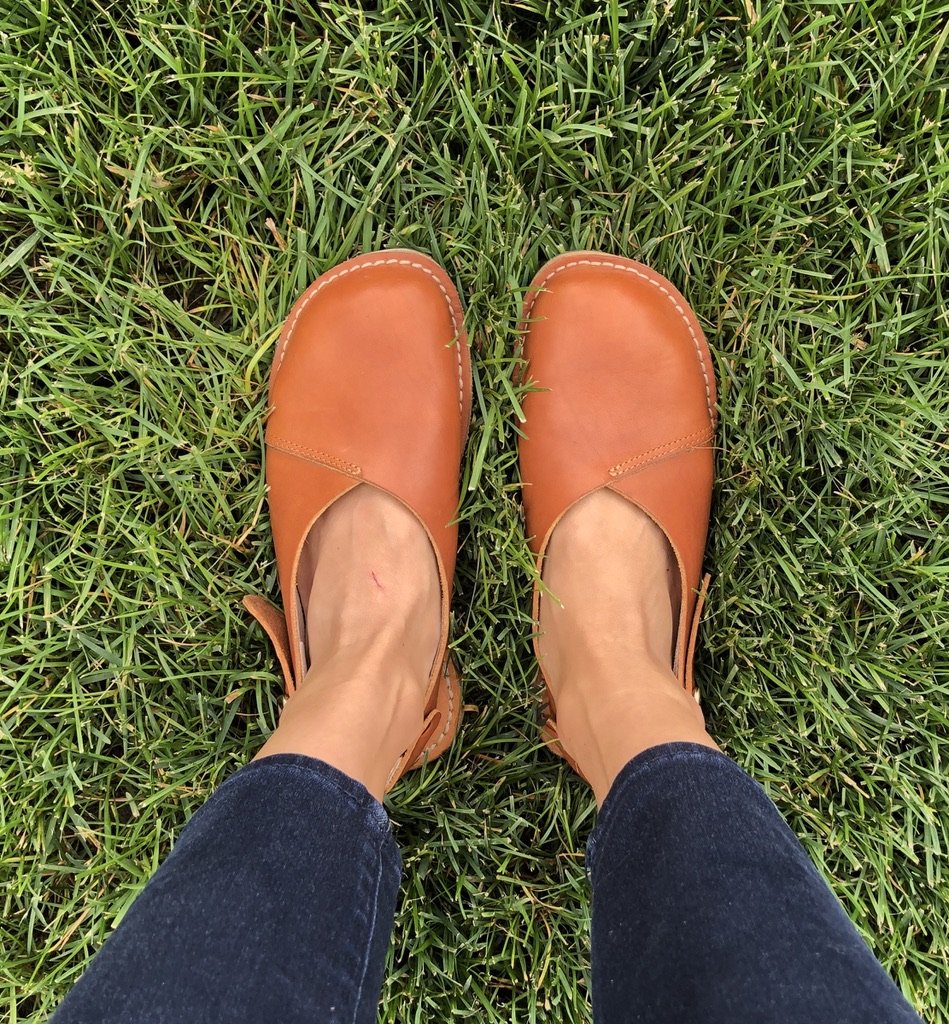 a top down image of a pair of feet wearing crupon sandals Trevi model in brown color to show women's barefoot dress shoe options