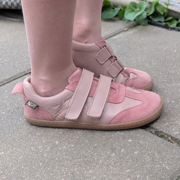 Side view of a young child in pink leather barefoot sneakers from Young Soles, a wide toe box flexible shoe for kids