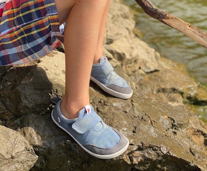 a close up of a child wearing splay athletics barefoot shoes for kids in blue