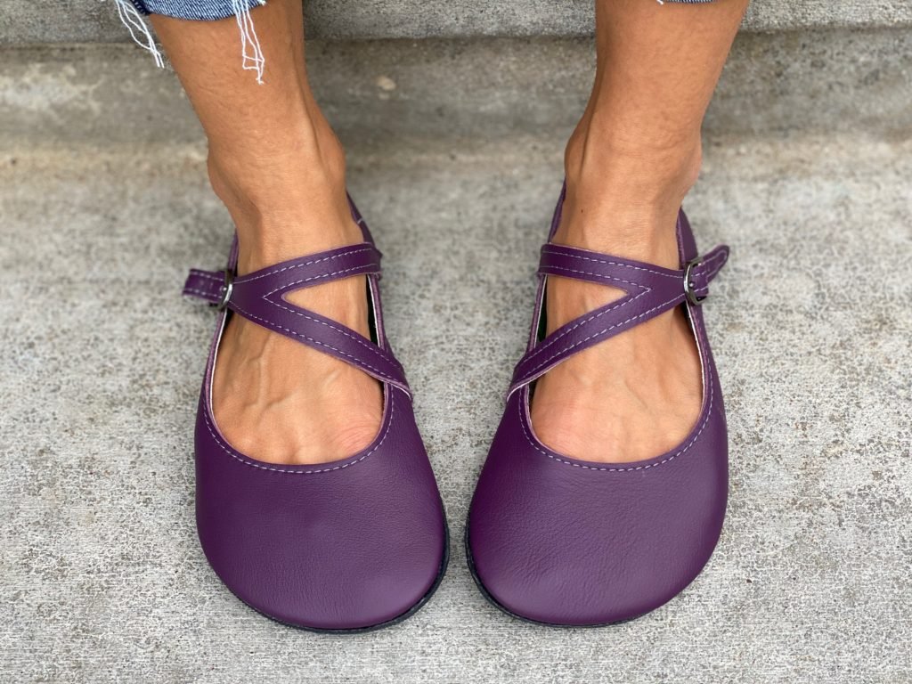 A front view of a pair of feet wearing the primal merry Jane in elderberry from softstar shoes on pavement