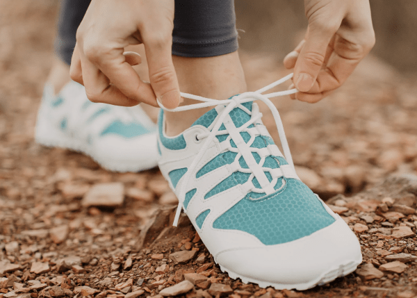 A photo of a pair of Ahinsa Chitra barefoot hiking shoes in white and teal vegan material
