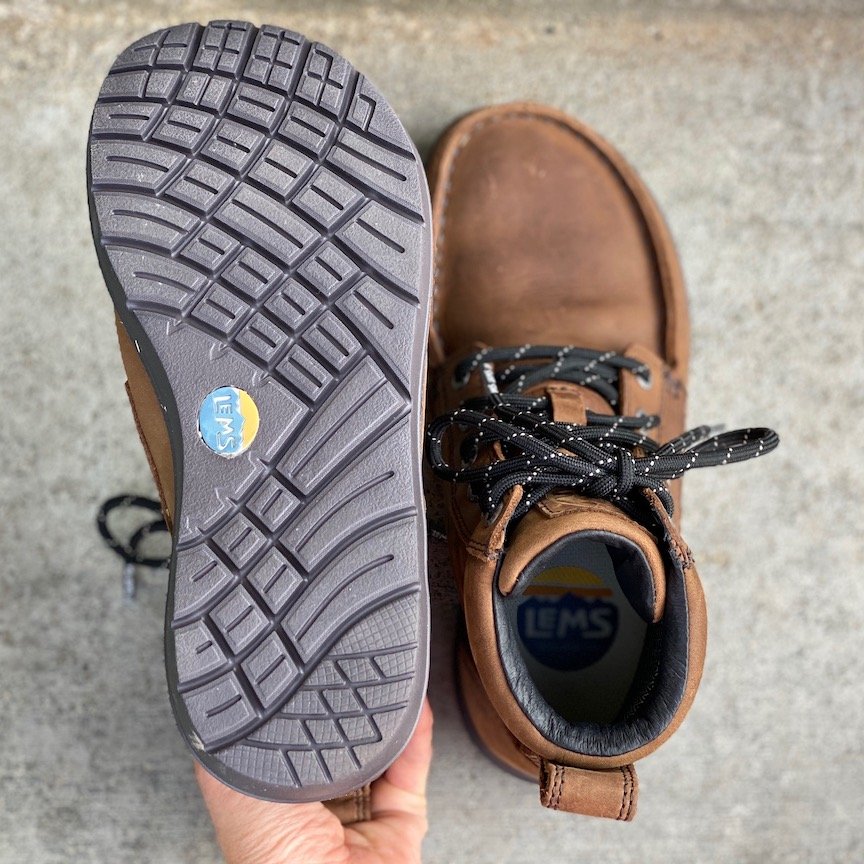 a close up of a pair of lems waterproof boulder sitting on concrete with the outsoles visible for the best barefoot minimalist hiking boots review