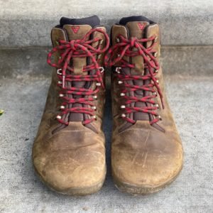 a close up of a pair of vivobarefoot trackers in brown sitting on concrete for the best barefoot minimalist hiking boots review