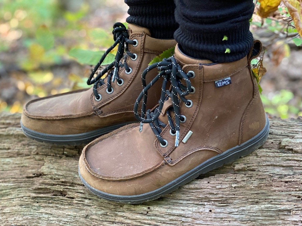 a close up of a pair of feet wearing the lems waterproof boulder boot in brown leather for the best barefoot minimalist hiking boots review