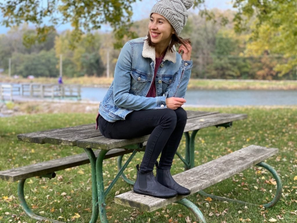 A woman sitting and smiling wearing Mukishoes vegan barefoot chelsea boot review