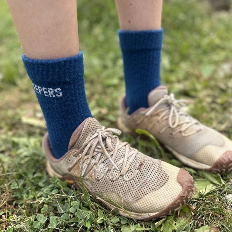 A person's feet wearing blue socks and Merrell Trail Glove barefoot friendly hiking sneakers