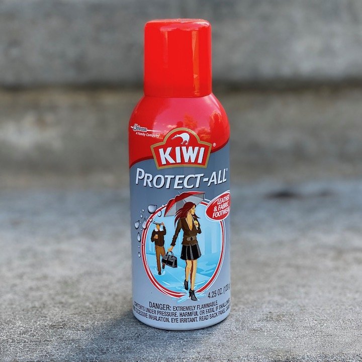 a close up of kiwi protect all shoe spray with a red lide, sitting on concrete