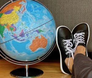 A close up of a globe of the world with a pair of feet wear Be Lenka barefoot Prime sneakers from Anya's Shop