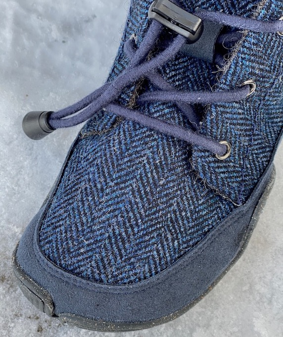 A close of up the toe box of the Nessie kids winter barefoot shoe from Wildling showing the blue houndstooth pattern and elastic laces.