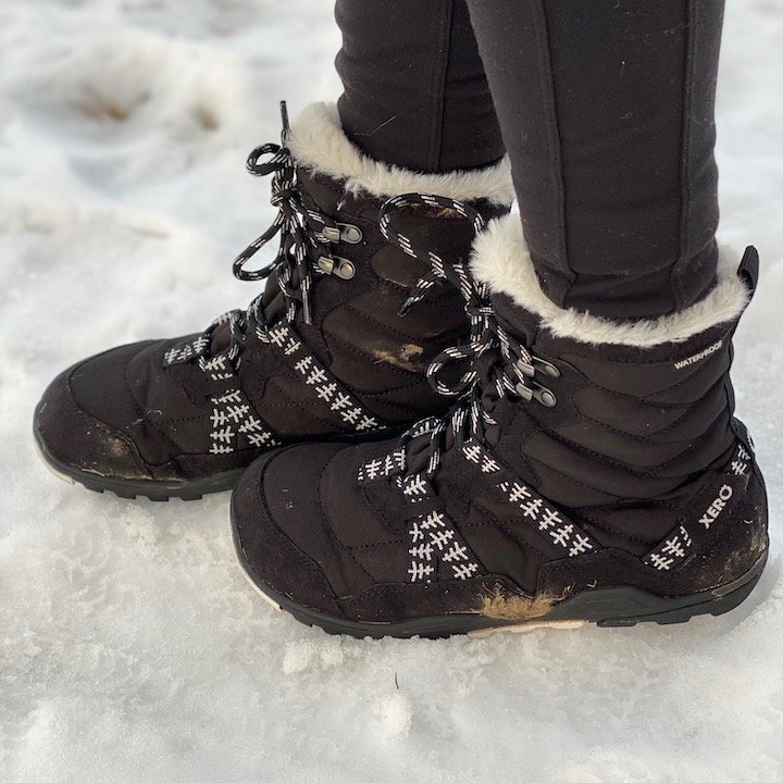 A side view of a pair of feet wearing the Xero shoes vegan barefoot winter snow boot