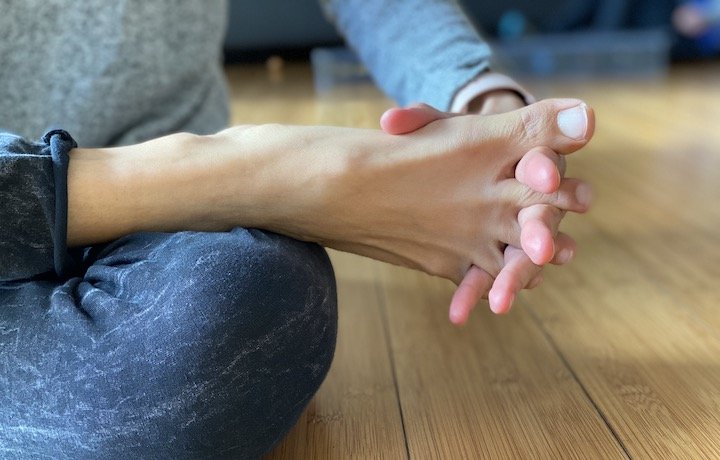 A close up of a woman spreading her toes using her fingers as spacers.