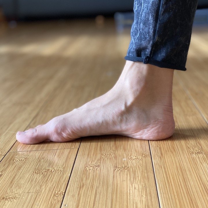 A close up side view of a woman's foot doing foot exercises to transition to barefoot shoes.