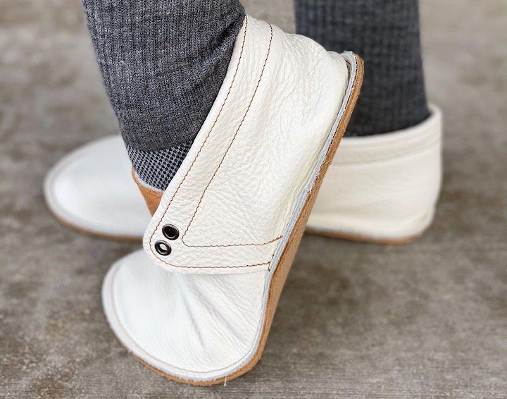 A woman wearing a pair of suede sole Posh Panda Moccasins flexing her foot to show how the shoe moves