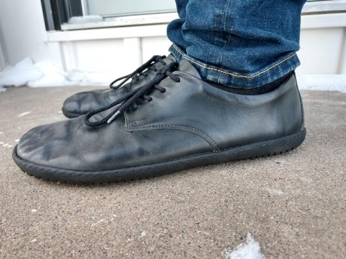 A close up side view of a man's feet wearing Groundies Palermo black leather dress shoes.