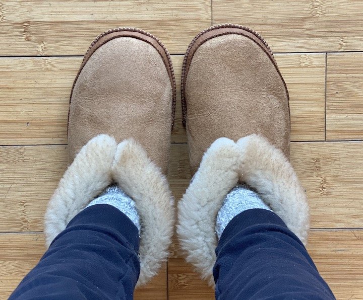 A top down view of a woman's legs in Softstar Fireside slippers, an incredibly soft and warm barefoot sheepskin slipper.