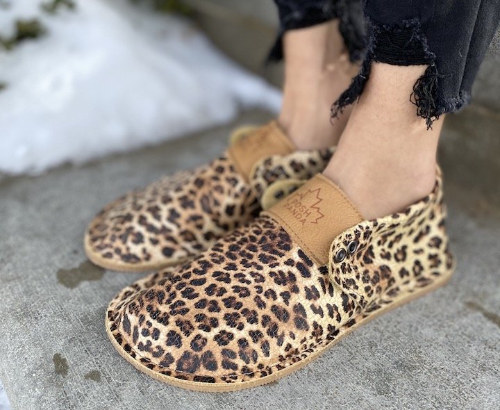 A close up angled view of a pair of Posh Panda leopard barefoot moccasins.