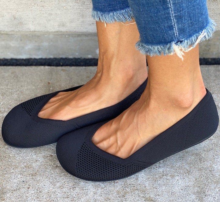 A close up angled side view of a woman's feet in Xero Phoenix black knit dress flats