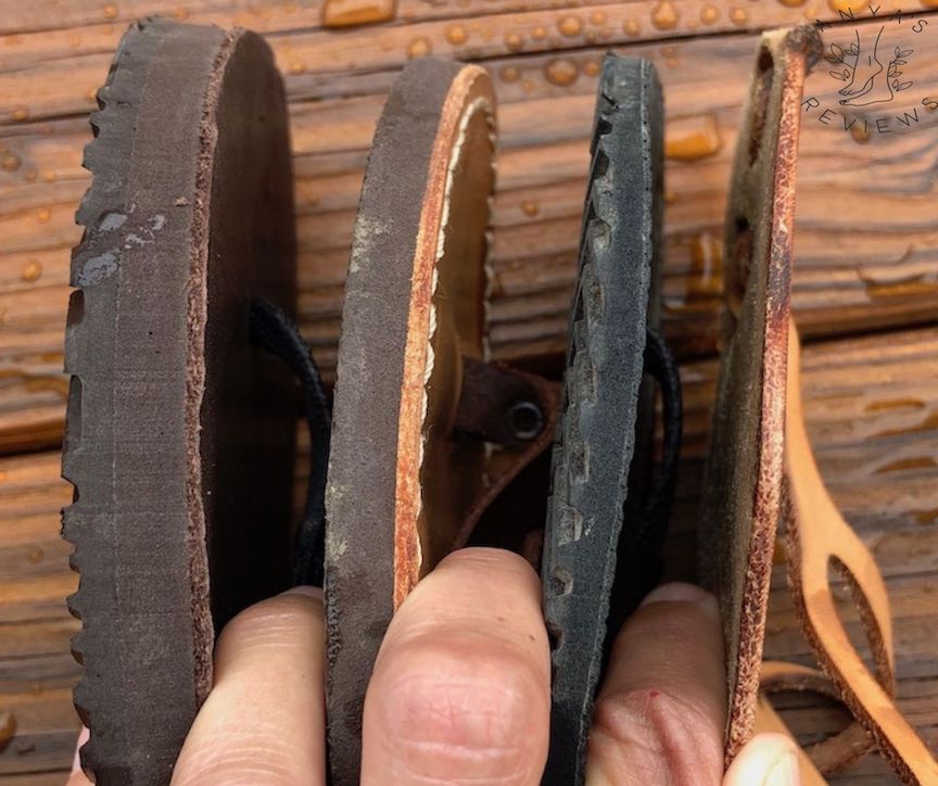 Closeup of a hand holding 4 pairs of sandals separated by their fingers to show varrying thickness among barefoot sandal brands