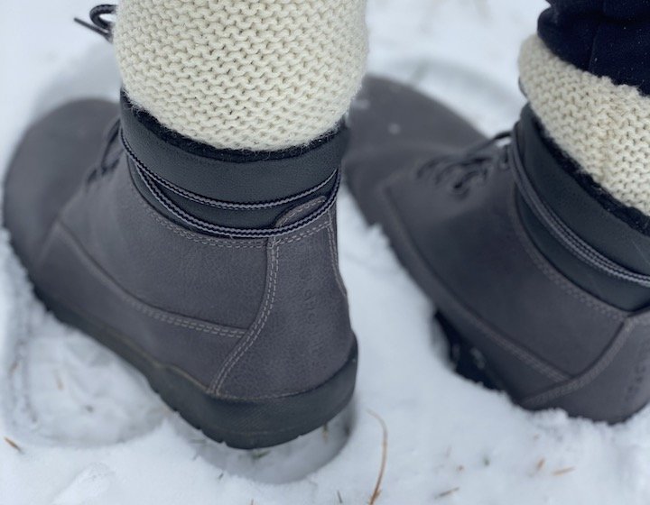 A close of from behind of a woman in thick socks and leggings wearing a pair of Feelgrounds Patrol vegan barefoot winter boots.