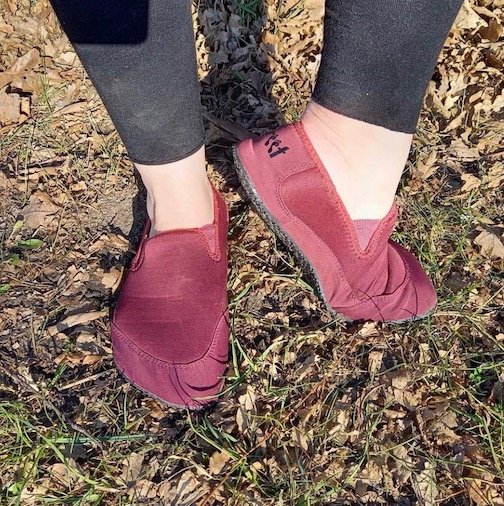 Freet Talus 2 in red being worn in the grass. They are very flexible and wide barefoot slip on shoes.