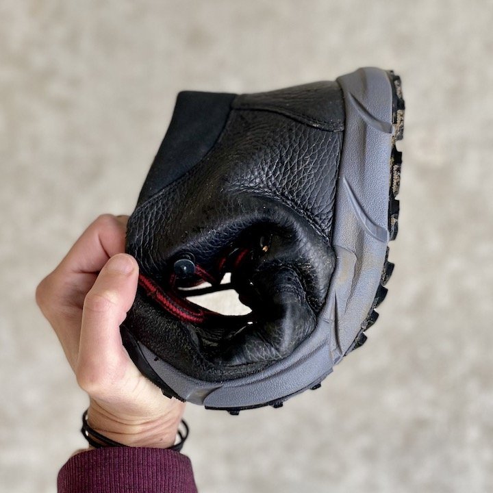 A woman's hand holding one Joe Nimble hiking boot into a J shape to show the slightly flexibile outsole.