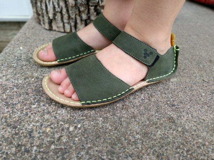 Side angled view of Vivobarefoot Ababa leather kids sandals being worn by a young child.