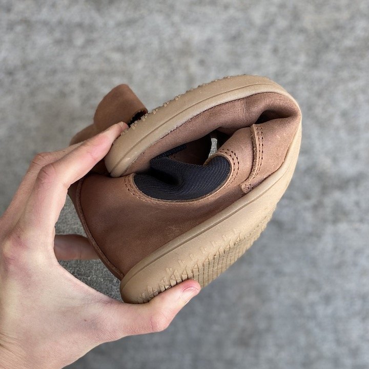 A close up of a woman's hand folding an Angles Fashion chelsea boot into a tight U shape to show the flexible sole