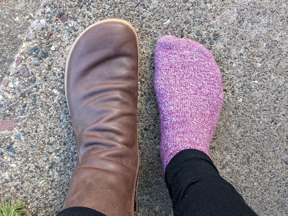 Top down view of an extra wide socked foot next to Angles Fashion Dafne zero drop barefoot boots