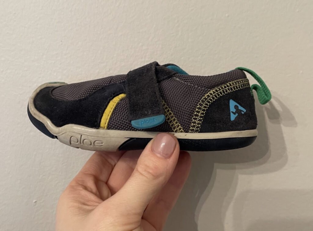 A picture of a dark blue, gray, and yellow plae shoe Ty model shown from the side with the shoe closed as small as it can