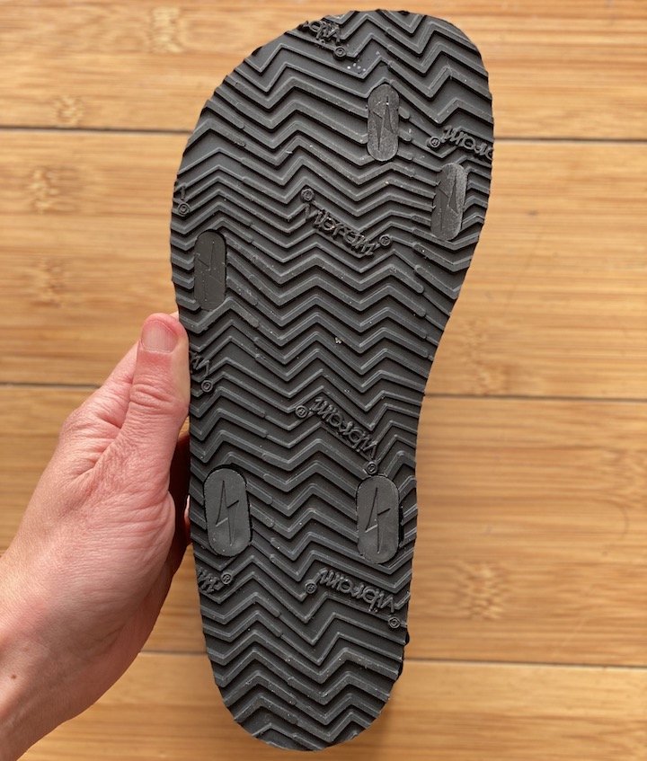 A hand holding up a single Shamma Sandals Trail Star with the Vibram outsole visible