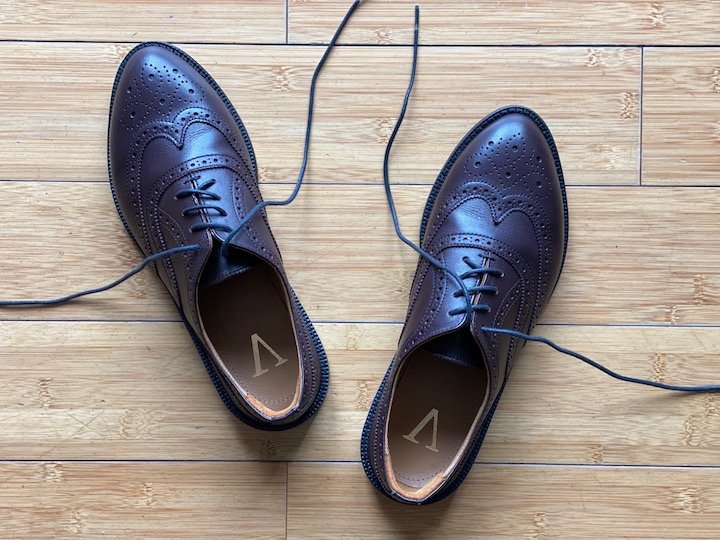 A top down view of a pair of Carest Victoria Wingtips in oxblood sitting on a wood floor