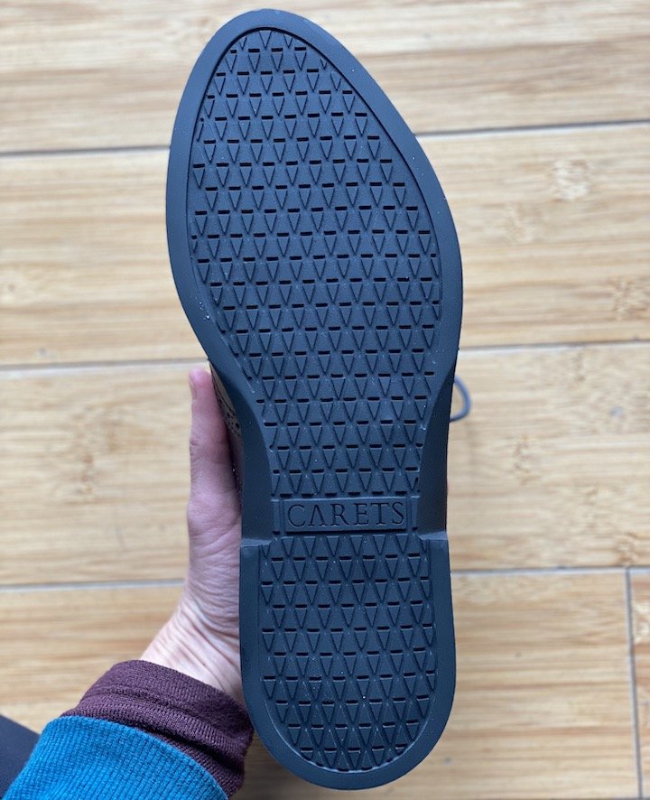 A top down view of a hand holding up the outsole of a Carets Victoria Wingtip shoe