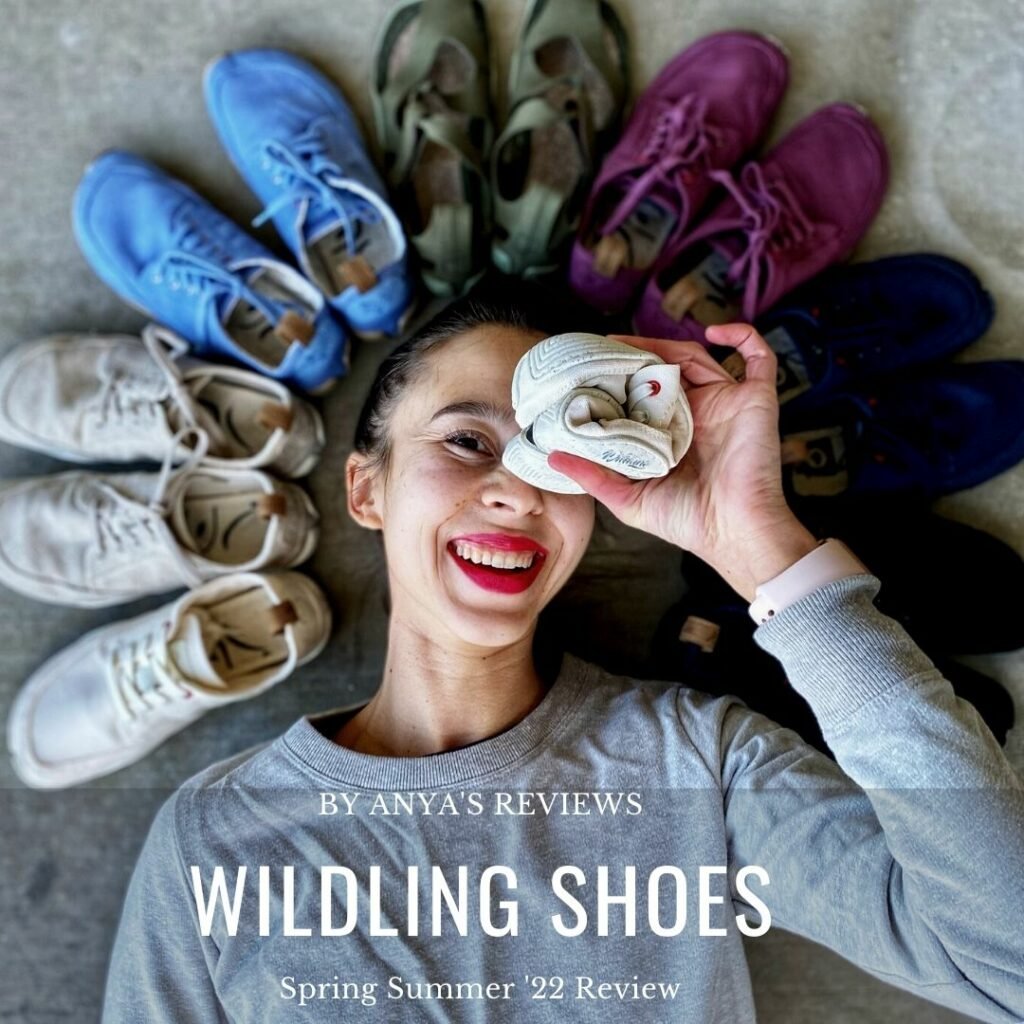 A close up of a woman's face lying on the ground, smilling at the camera with a circle of Wildling Shoes SPring Summer 2022 Collection. She is holding one white Wildling shoe rolled up into a ball over her left eye.