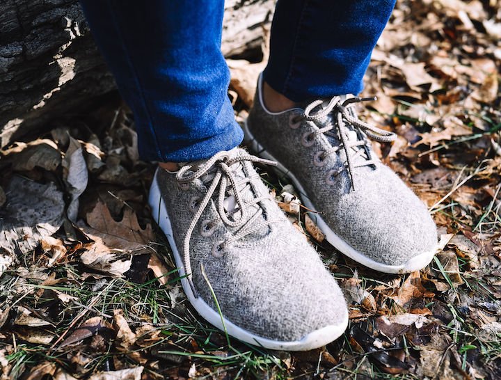 A side view of a pair of feet outside on grass wearing Groundies Performance Relax barefoot sneakers in taupe wool