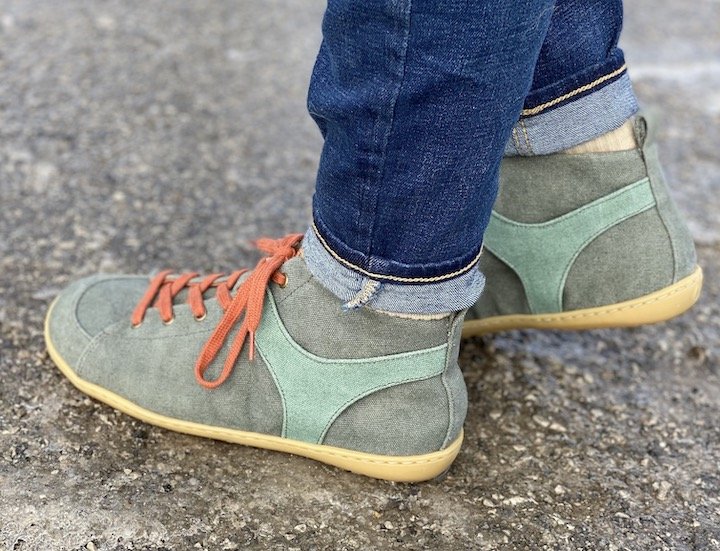 A side view of a person standing on asphalt wearing the Mukishoes Ivy high top barefoot sneakers