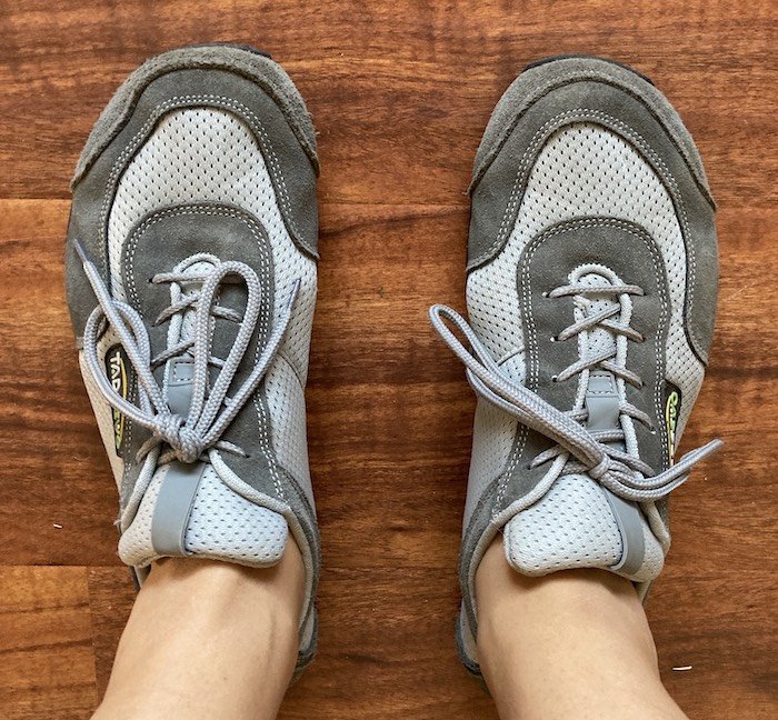 A top down view of a pair of feet wearing Tadeevo bliss barefoot running sneakers in grey