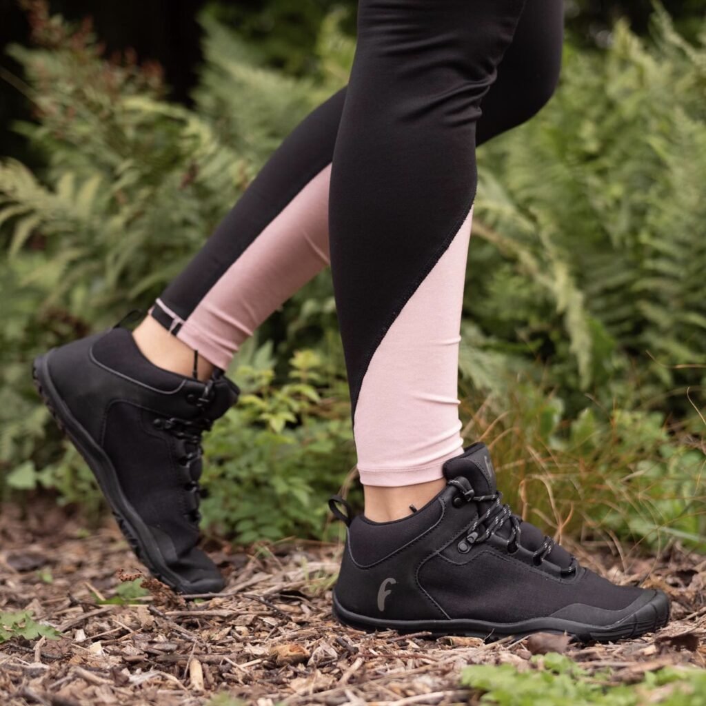 A close up of a person's feet walking in the forest wearing black vegan barefoot hiking boots from Freet Barefoot