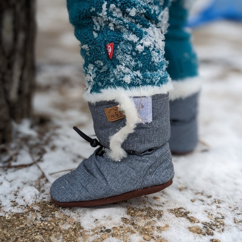 Close up of Jan & Jul affordable stay-put winter booties for babies toddlers standing on snowy ground