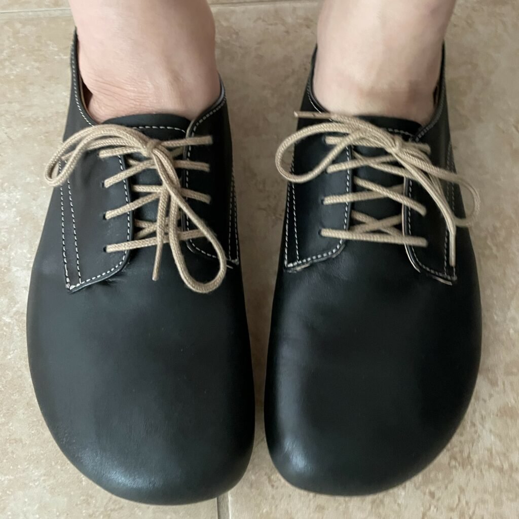 Front top down view of Nons Oxfords in black with tan laces being worn by a person with wide feet.