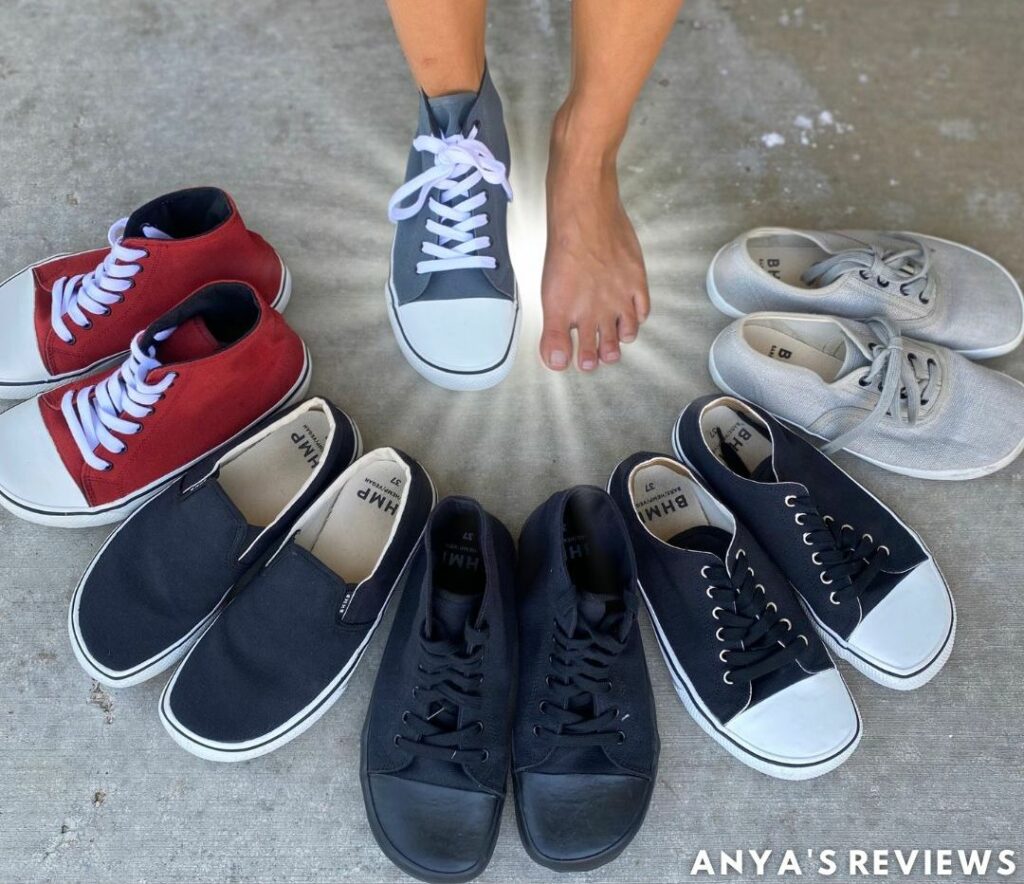 a semicircle of bohempia barefoot sneakers in different colors and styles surrounding a pair of feet - one foot is bare and the other is wearing a Bohempia sneaker in grey to show that it has a natural foot shape. Above is the text "Bohempia Sneaker Review, Anya's Reviews"