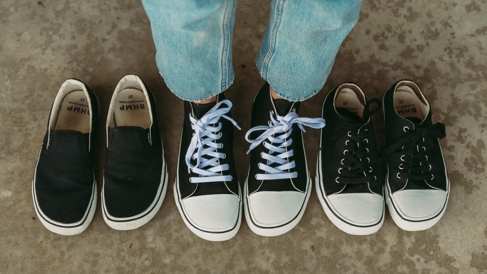 A pair of legs standing in Bohempia sneakers with 2 pairs of unworn Bohempia sneakers one each side. They all feature a wide toe box and converse and vans look.