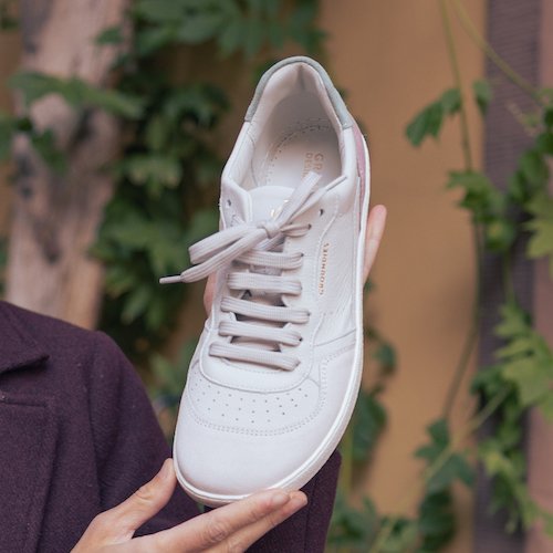 A close up of a hand holding a Groundies Nova stylish barefoot sneaker